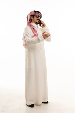 رجل سعودي بالثوب يتحدث في الجوال بخلفية بيضاء