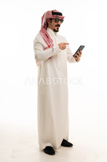 رجل سعودي بالزي التقليدي يحمل هاتف ذكي