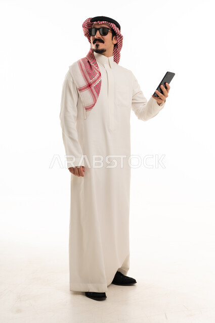 رجل سعودي بالثوب التقليدي يمسك هاتف ذكي
