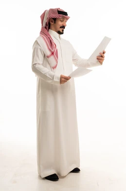 رجل سعودي مهني يقرأ مستندات ورقية على خلفية بيضاء