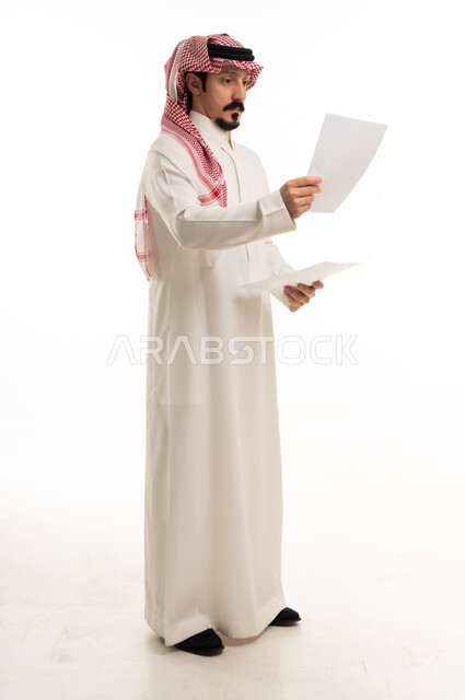 Saudi Man in Thobe Reading Documents on White Background