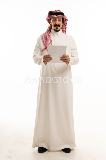 رجل سعودي بالزي التقليدي يحمل ورقة بيضاء فارغة
