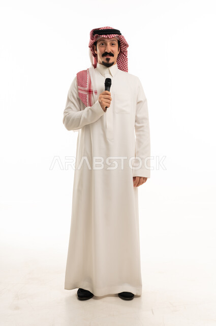 رجل سعودي بالثوب التقليدي يمسك ميكروفون في استوديو