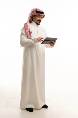 رجل سعودي بالزي التقليدي يستخدم جهاز لوحي رقمي