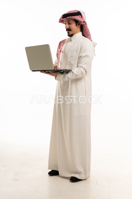 رجل سعودي بالزي التقليدي يستخدم الحاسوب المحمول خلفية بيضاء
