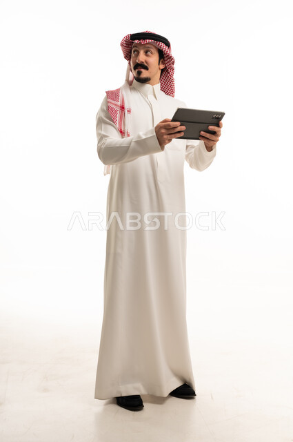 رجل سعودي يحمل جهاز لوحي بخلفية بيضاء