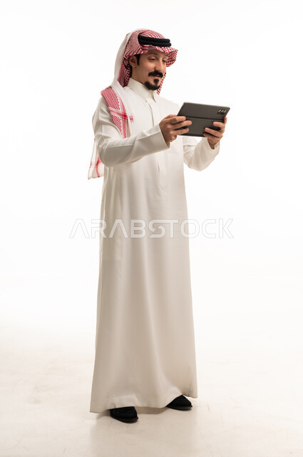 رجل سعودي يستخدم جهاز لوحي على خلفية بيضاء
