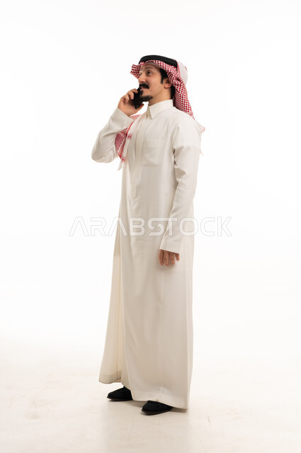 Saudi Man in Traditional Thobe Talking on Smartphone