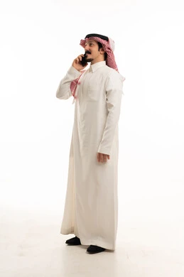 رجل سعودي بالثوب التقليدي يتحدث عبر الهاتف الذكي