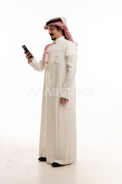 Saudi Man in Traditional Thobe Using Smartphone