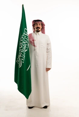 رجل سعودي يحمل العلم الوطني على خلفية بيضاء