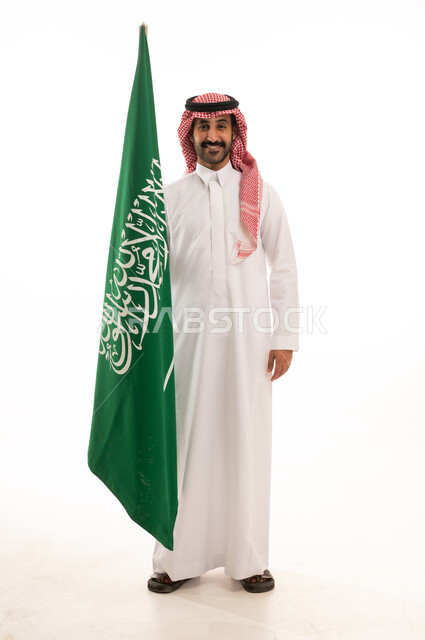 رجل سعودي يحمل علم المملكة العربية السعودية بالزي التقليدي
