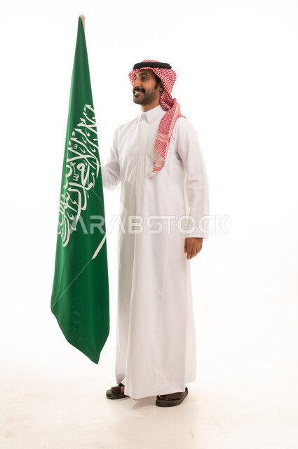 رجل سعودي بالزي التقليدي يحمل علم السعودية