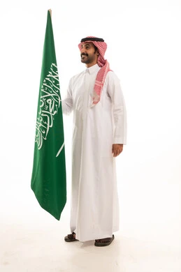 رجل سعودي بالزي التقليدي يحمل علم السعودية