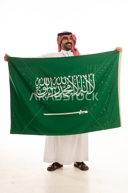 رجل سعودي يحمل العلم الوطني بالزي التقليدي