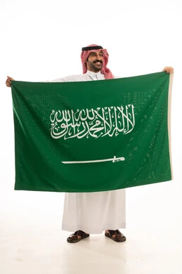 رجل سعودي يحمل العلم الوطني بالزي التقليدي