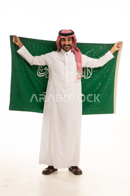 رجل سعودي بالزي التقليدي يحمل علم المملكة