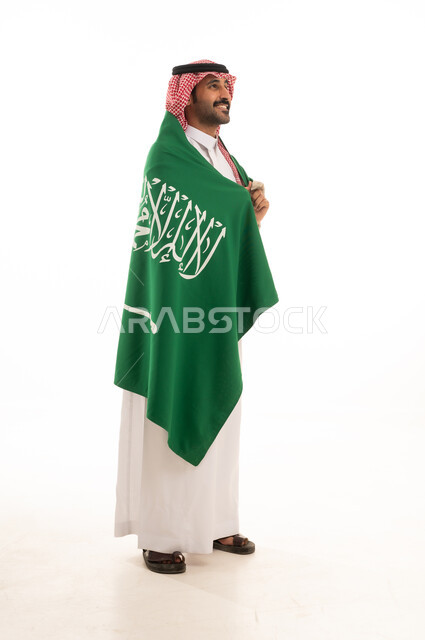 رجل سعودي بالعلم الوطني بالثوب والشماغ