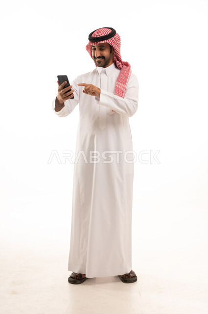 Saudi Man in Traditional Thobe Using Smartphone