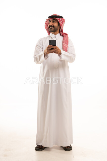 رجل سعودي بالثوب التقليدي يمسك هاتف ذكي