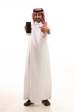 رجل سعودي بالثوب يمسك ويشير إلى هاتف ذكي