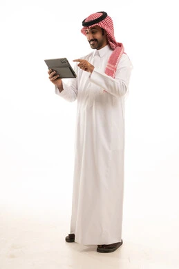 رجل سعودي بالزي التقليدي يستخدم جهاز لوحي
