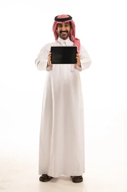 رجل سعودي بالثوب والشماغ يحمل جهاز لوحي تابلت