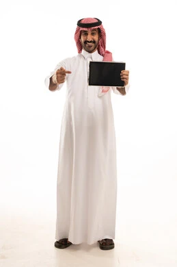 رجل سعودي بالثوب يشير إلى جهاز لوحي رقمي