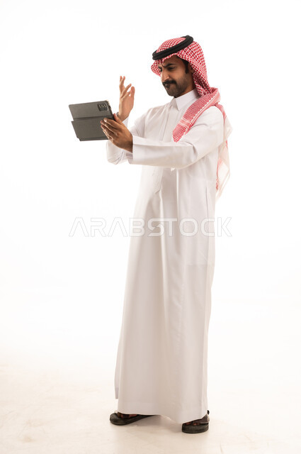رجل سعودي بالثوب والشماغ يستخدم جهاز لوحي
