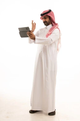 رجل سعودي بالثوب والشماغ يستخدم جهاز لوحي