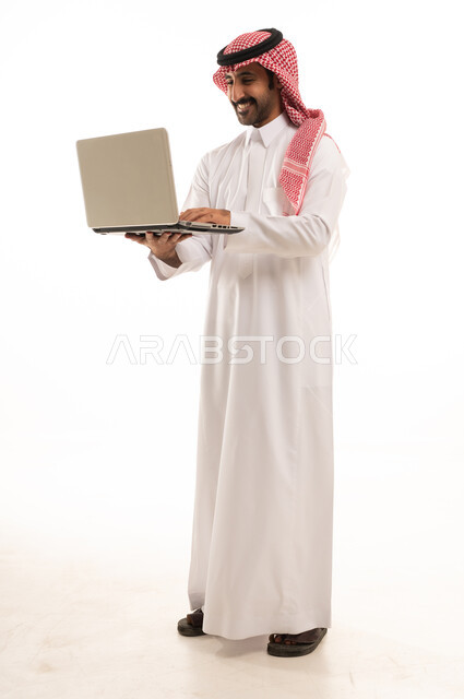 رجل سعودي بالزي التقليدي يستخدم جهاز كمبيوتر محمول