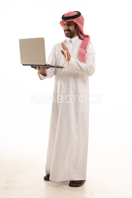 رجل سعودي بالثوب والشماغ يستخدم جهاز المحمول