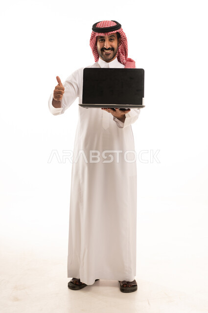 رجل سعودي بالثوب يمسك لابتوب مع إشارة الإعجاب