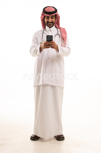طبيب سعودي بالزي التقليدي يستخدم الهاتف الذكي