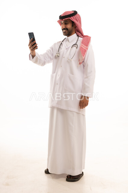 طبيب سعودي بالثوب والشماغ يستخدم الهاتف الذكي