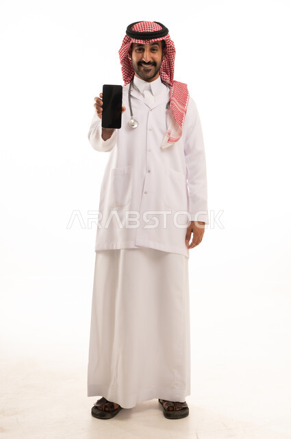 طبيب سعودي يمسك هاتفاً ذكياً بخلفية بيضاء