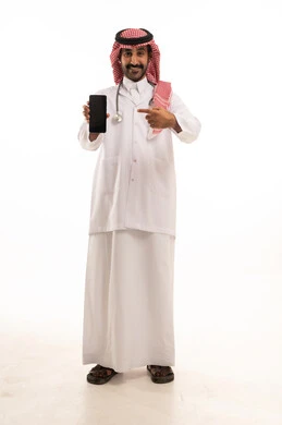 طبيب سعودي يرتدي الثوب والشماغ يحمل هاتفاً ذكياً