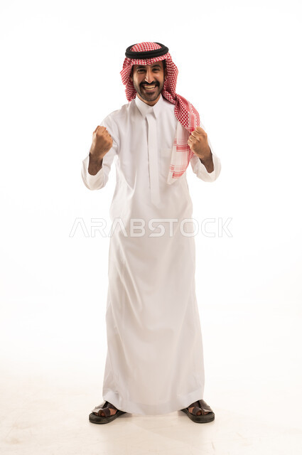 الحماس والتفاعل مع المنتخب، مشاهدة ومتابعة مباراة كرة القدم، بورتريه لرجل عربي خليجي سعودي مبتسم يرتدي الثوب التقليدي والشماغ يرفع يديه بإيماءات الشغف والتشجيع للفريق، خلفية بيضاء