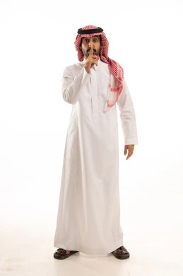 الصمت والتوقف عن الكلام, الأمر بالنهي عن فعل شيء ما, بورتريه لرجل عربي خليجي سعودي يرتدي الثوب والشماغ التقليدي يرفع اصبعه للأعلى, طلب خفض الصوت والتهديد, صورة لكامل الجسم, خلفية بيضاء
