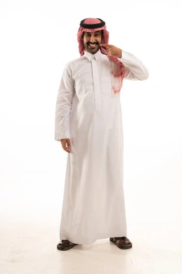 تجميل وتبييض الأسنان، بورتريه لرجل عربي سعودي خليجي يرتدي الزي التقليدي والشماغ  يشير بإصبع السبابة على أسنانه البيضاء، مفهوم العناية والإهتمام بالصحة والمظهر الخارجي ، الحصول على إبتسامة هوليود باستخدام قشور فينير من الخزف، خلفية بيضاء