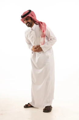 بورتريه لرجل عربي سعودي خليجي يرتدي الزي التقليدي والشماغ بايماءات وجه ويدين تدل على الشعور بألم البطن , الإحساس بالمرض والتسمم , الحاجه للعلاج وطلب المساعده , صوره بالطول الكامل، خلفية بيضاء