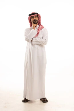 تعابير شرود الذهن والتمعن، ايجاد حل لمشكلة ما، التأمل والتخطيط للمستقبل، بورتريه لرجل عربي خليجي  سعودي يرتدي الزي التقليدي والشماغ يضع يده على ذقنه بايماءات التفكير والتركيز، صورة لكامل الجسم، خلفية بيضاء