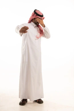 الصمت والتوقف عن الكلام, الأمر بالنهي عن فعل شيء ما, بورتريه لرجل عربي خليجي سعودي يرتدي الثوب والشماغ التقليدي يرفع كفه للأعلى, طلب خفض الصوت والتهديد, صورة لكامل الجسم, خلفية بيضاء