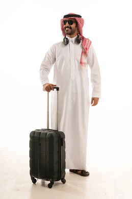 الاستعداد لقضاء رحلة صيفية ممتعة، مفهوم السياحة في إجازة الصيف، القيام بالجولات الترفيهية، بورتريه لرجل عربي خليجي سعودي يرتدي الزي التقليدي والشماغ يحمل شنطة سفر بتعابير السرور، خلفية بيضاء