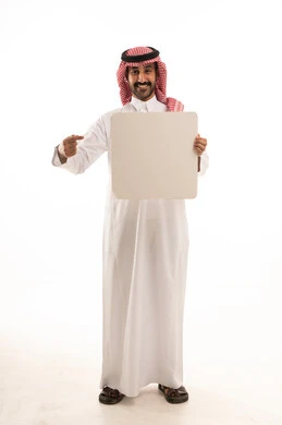 موك اب أبيض، لوح إعلاني فارغ، بورتريه لرجل عربي خليجي سعودي يرتدي الثوب التقليدي والشماغ يحمل بيده لوحه بيضاء، الوقوف باستقامه بايماءات الثقة بالنفس، صورة الجسم بالطول الكامل، خلفية بيضاء