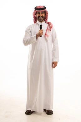 Gestures of integration and interaction with singing, recording a musical audio clip, a portrait of a Saudi Arabian Gulf man wearing traditional attire and a ghutrah, holding a microphone and singing enthusiastically, presenting theatrical artistic performances and entertainment segments, white background.