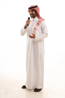 إيماءات الإندماج والتفاعل مع الغناء، تسجيل مقطع صوتي غنائي،  بورتريه لرجل عربي خليجي سعودي يرتدي الثوب التقليدي والشماغ ويمسك المايكروفون ويغني بحماس، تقديم العروض الفنية المسرحية والفقرات الترفيهية، خلفية بيضاء.