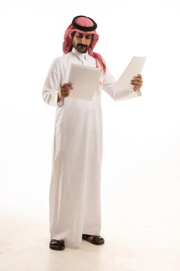 التدقيق في قراءة الملاحظات، بورتريه لسكرتير عربي خليجي سعودي يرتدي الثوب التقليدي والشماغ ويحمل بيده مجموعه من الاوراق البيضاء، اعداد التقارير الخاصة بالعمل، مراجعة ومتابعة الخطط والمشاريع المكتبية، خلفية بيضاء