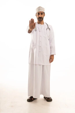 تعابير التوقف عن فعل شئ ما، بورتريه لطبيب عربي خليجي عماني يرتدي الدشداشة والعمامة والمعطف الطبي و الكمامة يضع السماعة الطبية يعمل في القطاع الصحي، الجسم بالطول الكامل، خلفية بيضاء