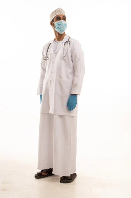 اتباع اجراءات السلامة للوقاية من فايروس كورونا،  بورتريه لطبيب عربي خليجي عماني يرتدي الدشداشة والعمامة والمعطف الطبي و الكمامة يضع السماعة الطبية يعمل في القطاع الصحي، الجسم بالطول الكامل، خلفية بيضاء
